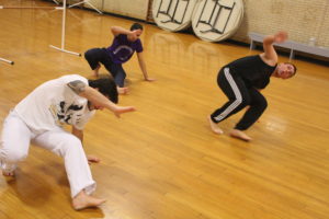 Three men wokring on a movement, balancing on one arm and one leg. 